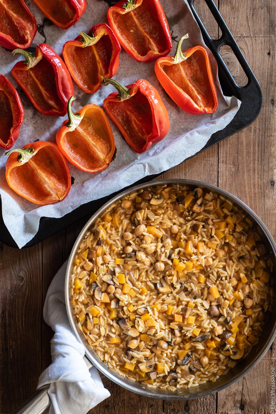 Roasted Red Peppers Stuffed with Mushroom, Pumpkin and Harissa Chickpea Orzotto www.thefoodiecorner.gr Photo description: A frying pan full of mushroom, pumpkin and harissa chickpea orzotto. Above the the pan is a baking tray with roasted red pepper halves.