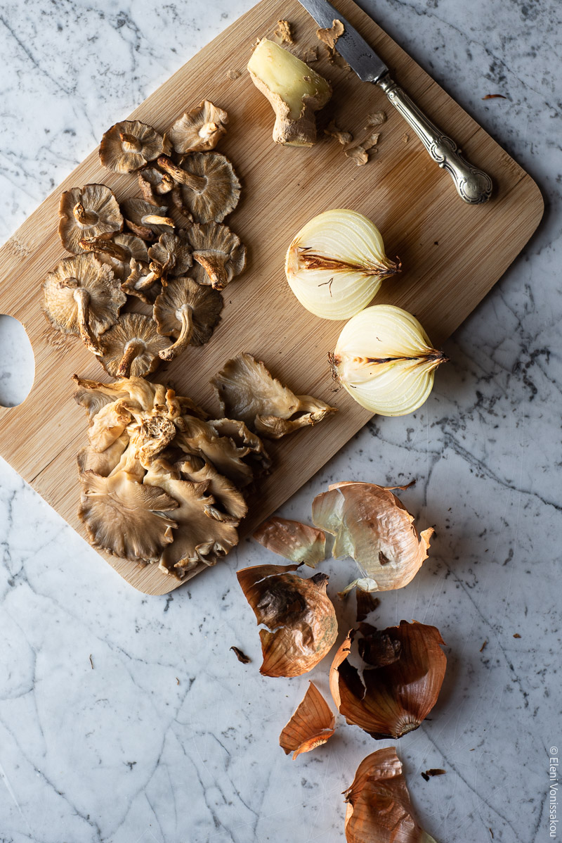 Mushroom Soup with Stelline Pasta, Inspired by Vietnamese Pho www.thefooodiecorner.gr Photo description: A chopping board with grilled mushrooms, charred onion and a piece of ginger with a knife next to it. On the marble surface next to the board are some charred onion peels.